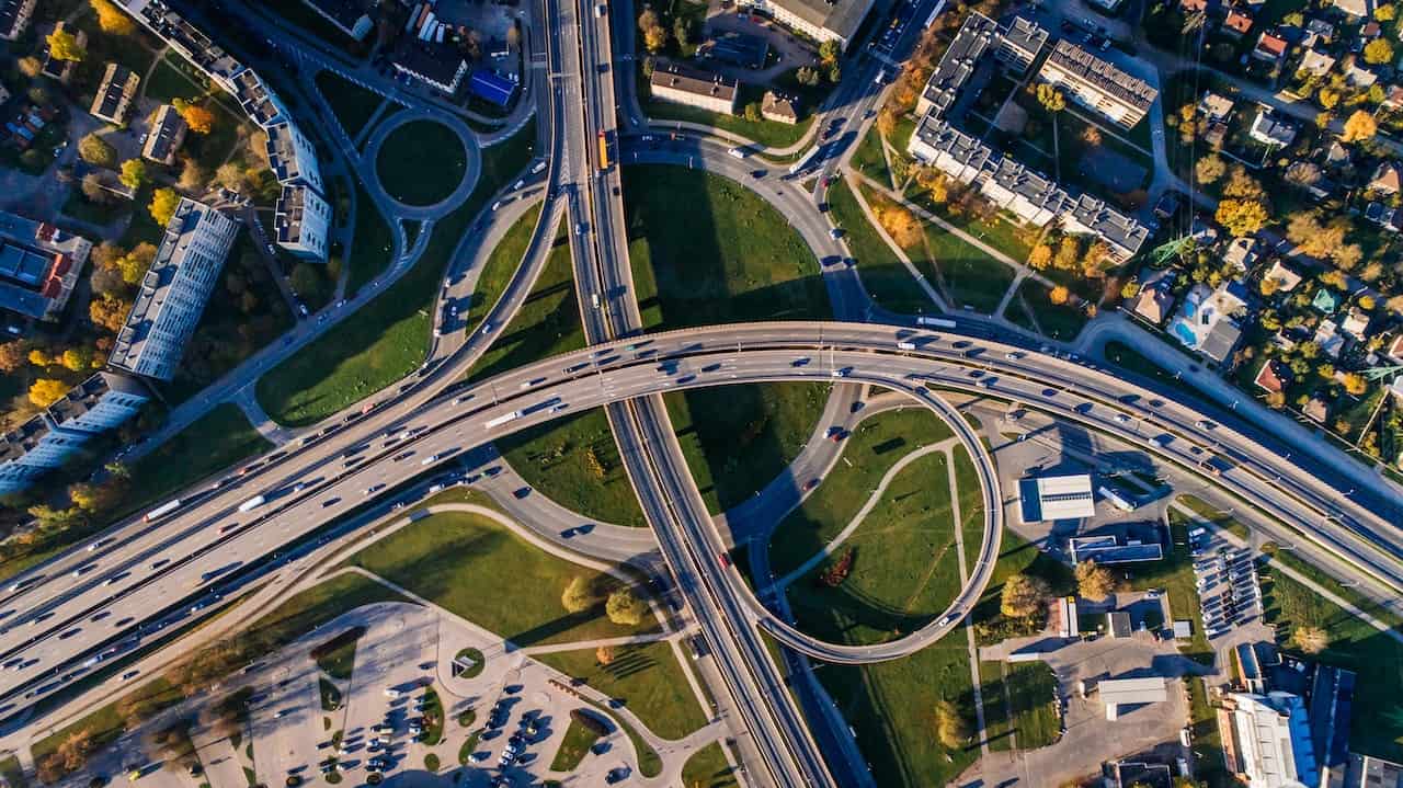 Aerial view of a complex highway interchange surrounded by buildings and greenery.