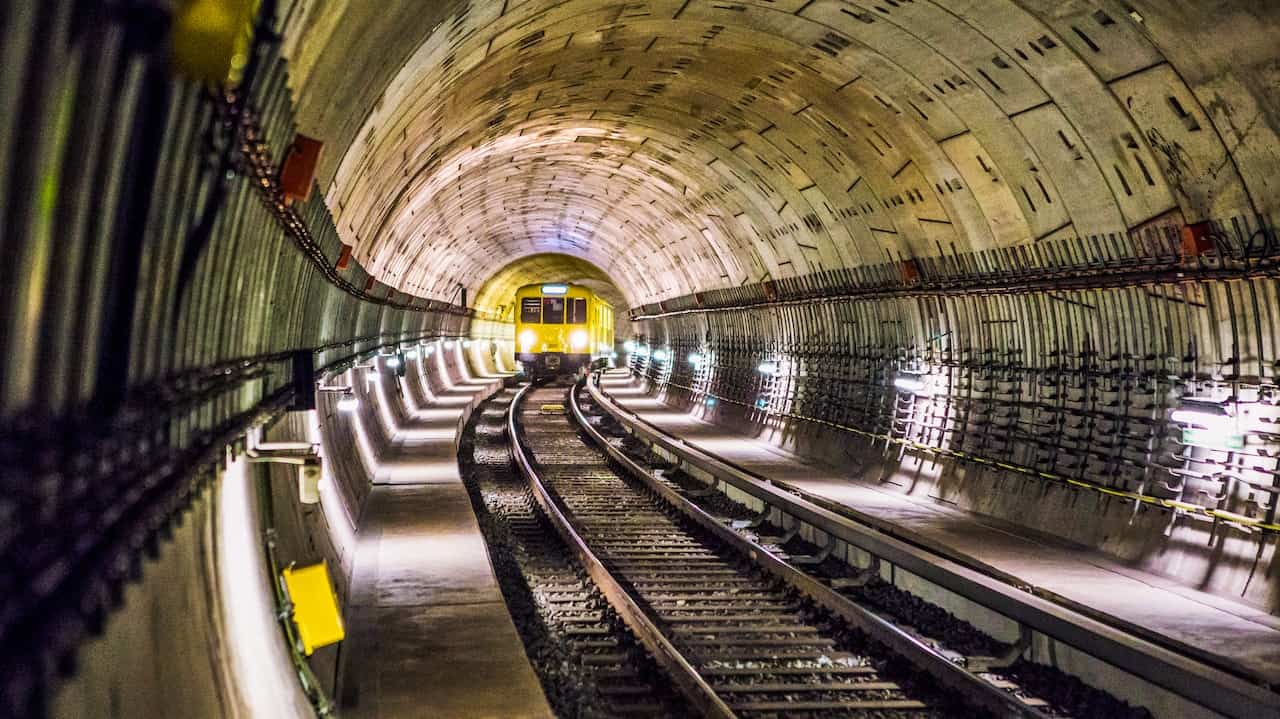 Train approaching through a well-lit underground tunnel.