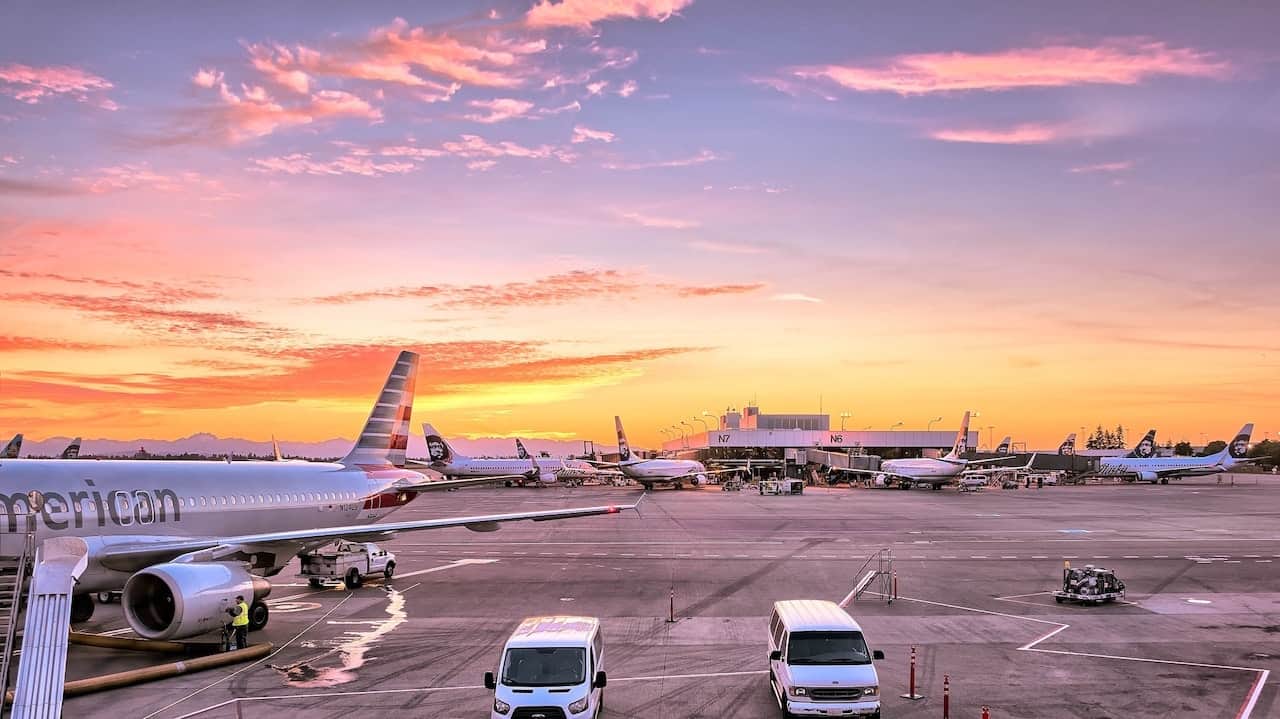 Airplanes parked at airport terminal during a vibrant sunset.